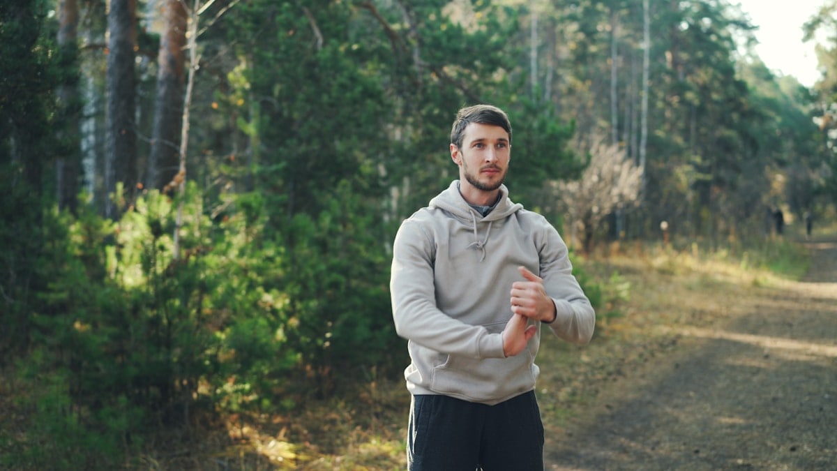 Man stretching outdoors in a forest setting.